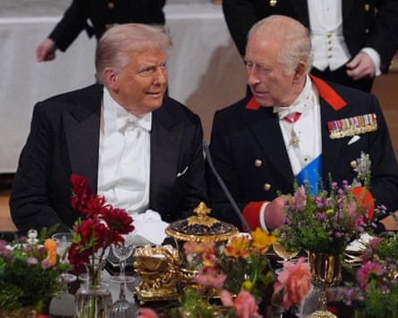 Donald Trump and King Charles seated side by side in evening dress in front of a banquet table, Trump wearing a goofy amazed expression as Charles leans towards him to speak