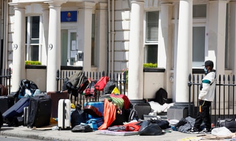 A man seeking asylum stands outside a London hotel in protest at the condition of his accommodation