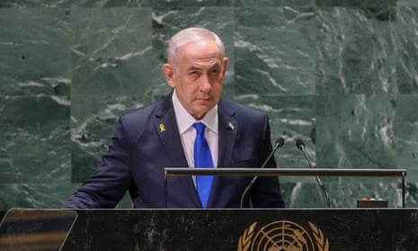 A man wearing a blue suit and tie stands at a podium