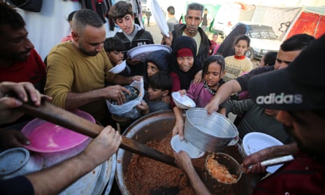 Palestinians sheltering at al-Aqsa hospital in Deir el-Balah, central Gaza, queue to receive food.