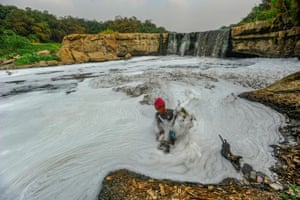 A resident catches fish at a once-scenic waterfall on the Cileungsi River, Curug Parigi, Indonesia, 27 August 2023.