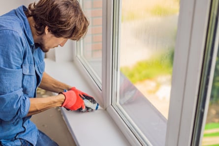 A man caulks any potential gaps around a window frame
