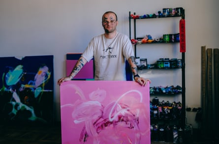Vladyslav Melnyk, an artist who is serving in the Ukraine air force, with one of his paintings, a large pink abstract.