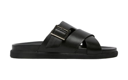 The side view of a black leather sandal with a buckle on the upper strap. It is on a white background.
