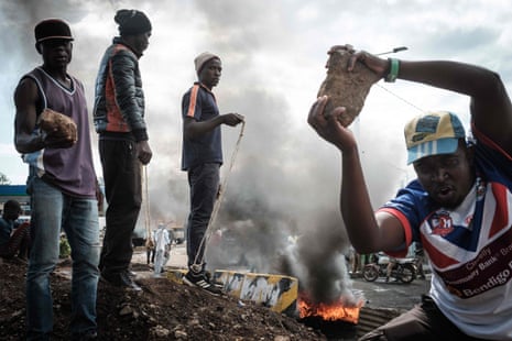 Opposition supporters hold up bricks as they block streets and burn tyres during a protest in Kisumu, Kenya