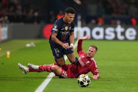 Alexis Mac Allister of Liverpool receives a yellow card for a foul on Desire Doué of PSG.