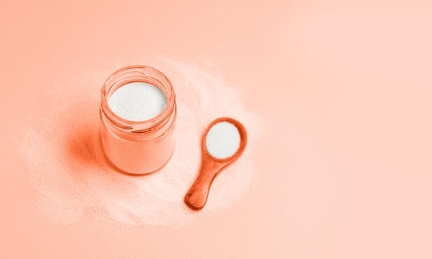 An open jar of collagen powder with a full spoon