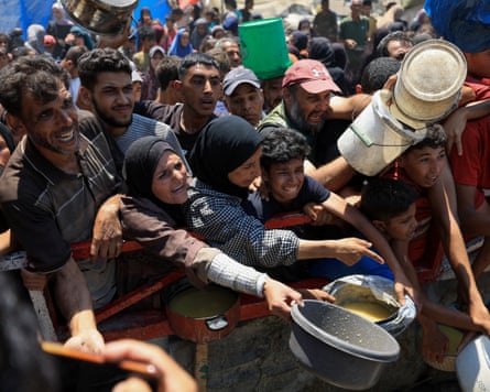 People stand holding out containers for food