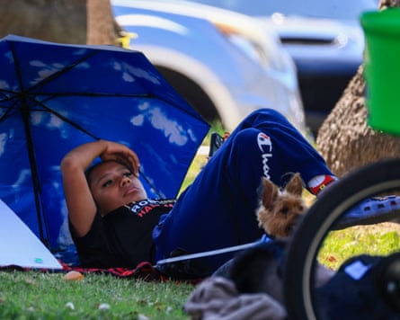 A woman shields herself and her dog with an umbrella