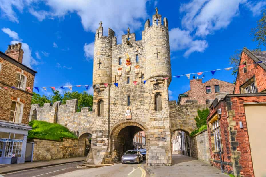 Micklegate, York, UK, on a blue-sky day; a car drives through the gate.
