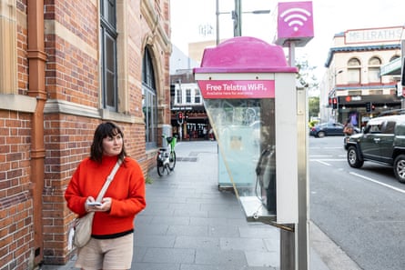 Caitlin Cassidy walking by a bright pink and purple phone booth