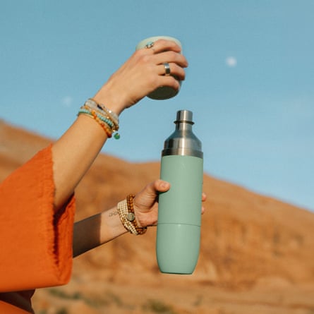 person uncapping teal tumbler outside