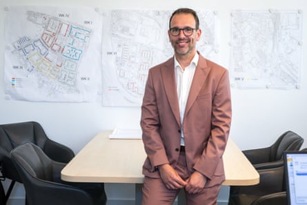 Enrico Hartrampf sitting on a desk in an office with a map of the city on the wall behind him