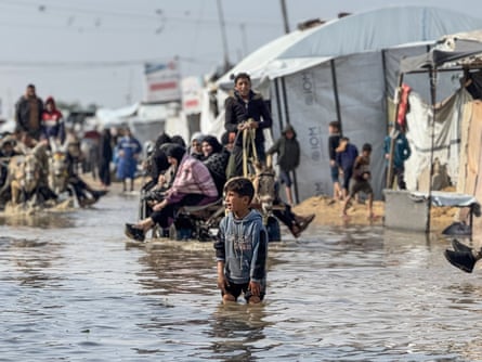 A boy wades thigh-deep in flood water