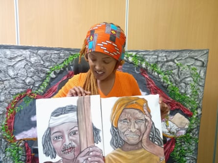A young African woman holds two paintings as she describes her art