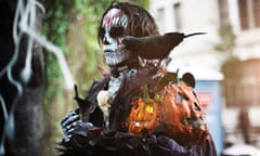 Man in Halloween costume with white blood-stained face mask, holds a carved pumpkin, Halloween Parade, New York.