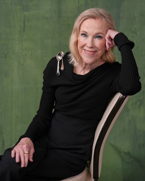 person wearing a black dress poses while sitting on a chair