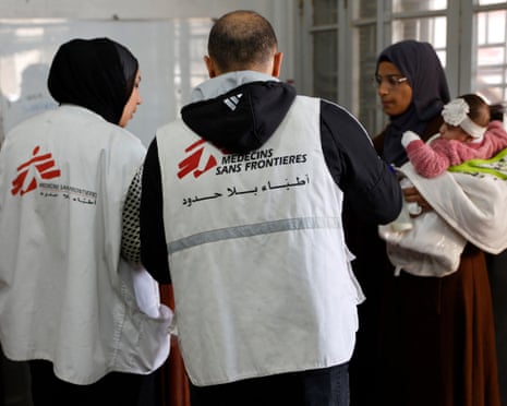 A Palestinian woman with a child speaks to two aid workers from Médecins Sans Frontières
