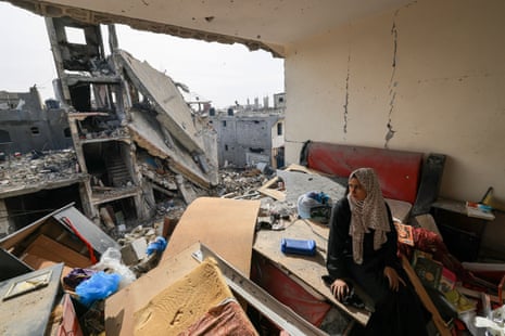A Palestinian woman sits on debris in her damaged apartment in the Khezaa district on the outskirts of the southern Gaza Strip city of Khan Younis.