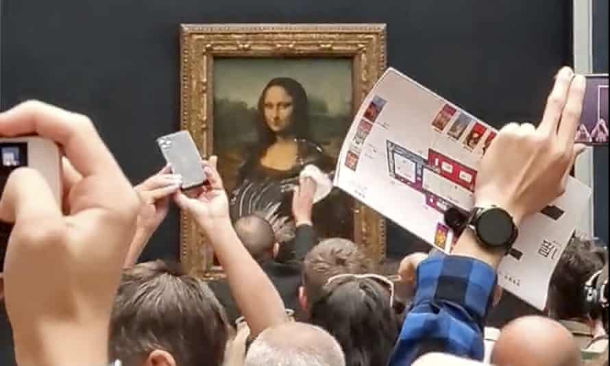A security guard cleans the smeared cream from the glass protecting the Mona Lisa at the Louvre Museum