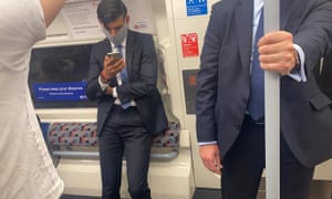 Rishi Sunak travelling on the tube wearing a mask.