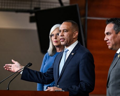 a man speaks into a microphone as a woman and a man stand near him