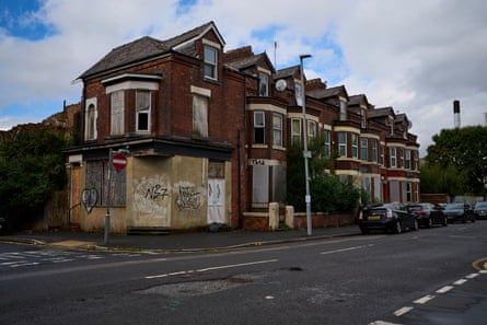 A row of boarded-up terrace houses with bay windows