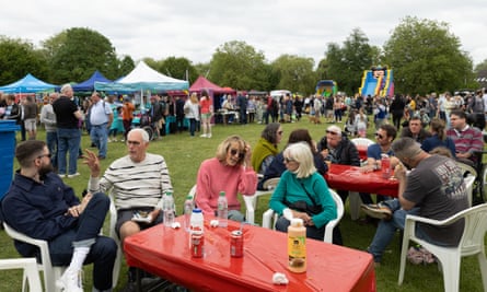 People sitting around tables outdoors at the Godalming town show.