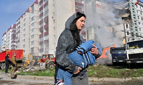 A woman carries a child near the residential building struck in Uman