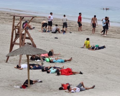 A group of migrants rests on a beach near the Tarajal border crossing in Ceuta, Spain.