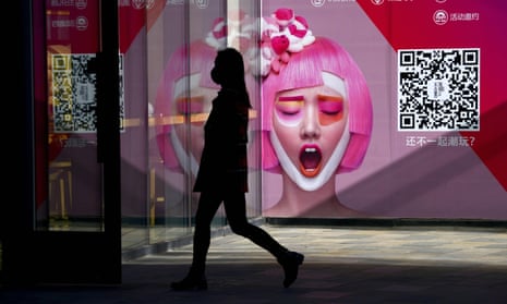 A woman passes a poster ad for a Beijing clothing store.
