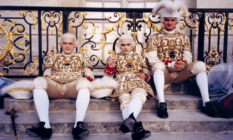 Three actors in period costume resting on steps against an ornate railing.