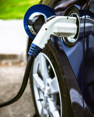 A modern electric car hooked up to a charging terminal has its battery refueled.