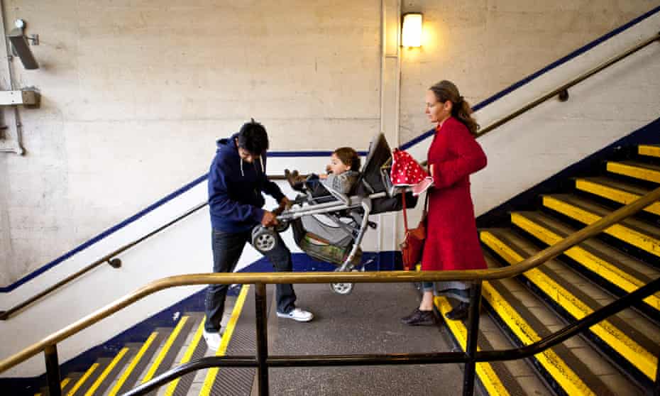 Carrying a push chair down the stairs in a London tube station.