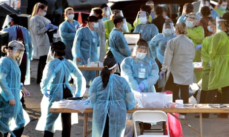 In this photo taken Saturday, June 27, 2020, medical personnel prepare to test hundreds of people lined up in vehicles in Phoenix, Arizona’s western neighborhood of Maryvale for coronavirus.