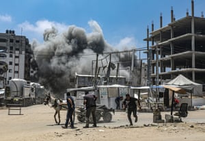 People run away from a plume of smoke amid destroyed buildings