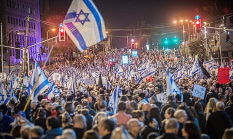 Folle di manifestanti sventolano bandiere israeliane durante una manifestazione a Tel Aviv