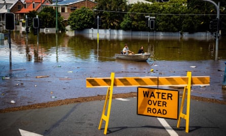 A couple steer their boat through a flooded street in Paddington, suburban Brisbane, in February