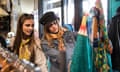 Young women friends browsing vintage clothes in thrift store