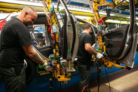 people work on a car on a factory floor