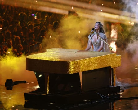 Goodrem stands at a sparkling, golden piano as she performs her song Eclipse at Eurovision