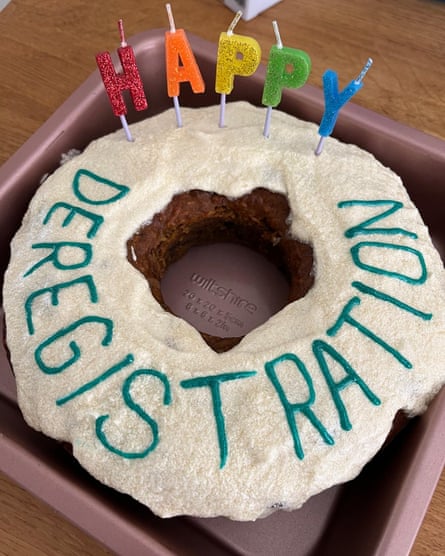 Round cake decorated with the word “deregistration”. The candles spell “happy”.
