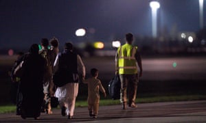 Passengers evacuated from Afghanistan are escorted across the tarmac after disembarking a British military transport aircraft at RAF Brize Norton station in southern England in the early hours of the morning.