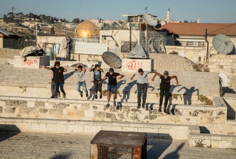 Palestinian boys practice parkour on the Galizia roofs, opposite the Dome of the Rock, in the Old City