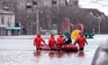 Emergency workers use a boat to evacuate people in floodwater