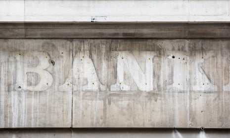 An old 'bank' sign with the letters removed, leaving only an outline ont he building