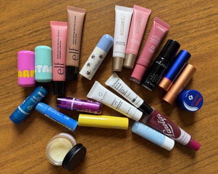 A selection of 21 lip balms on a wooden surface