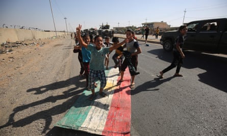 Iraqi children step on a Kurdish flag as forces advance towards the centre of Kirkuk during an operation against Kurdish fighters on Monday.