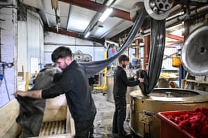 Workers handling rolls of Harris tweed cloth in a mill