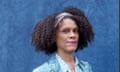A portrait of Bernardine Evaristo with a navy blue back drop, she is wearing a blue patterned shirt and jacket.